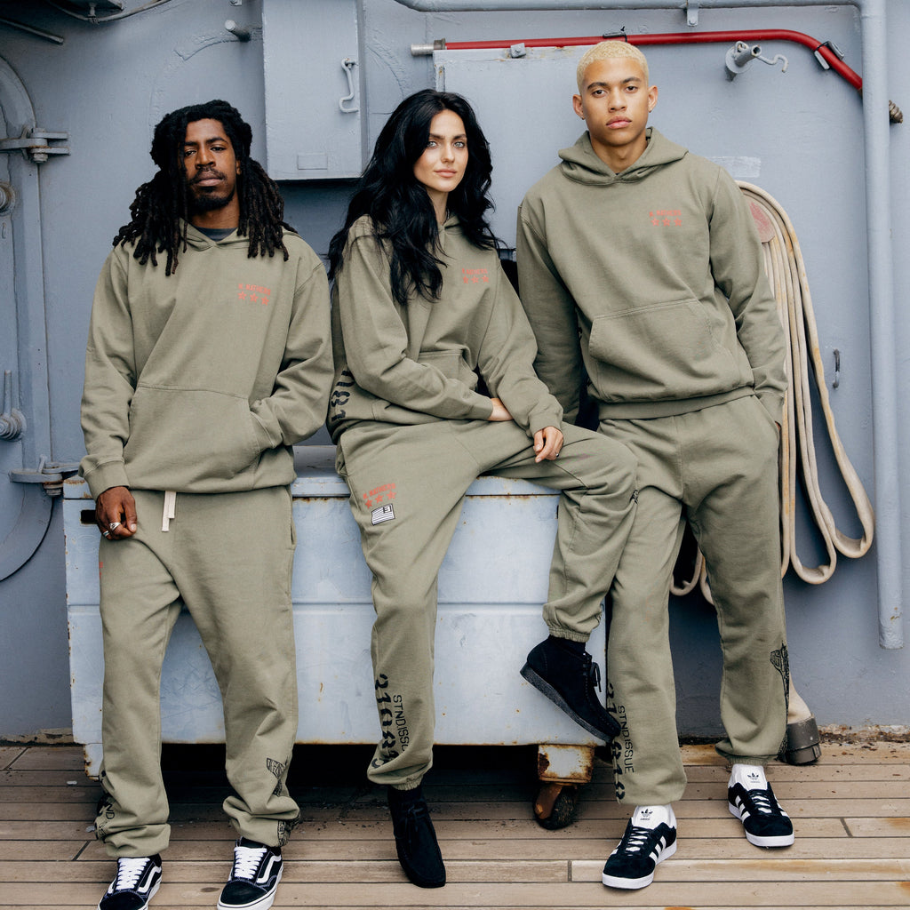 Three models in burnt olive Eminem Kamikaze x Standard Issue sweatpants and hoodies