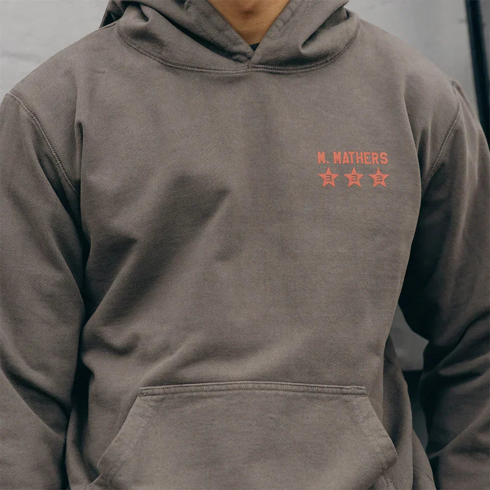 Orange chest print detail with stars on the taupe Eminem Kamikaze Standard Issue hoodie