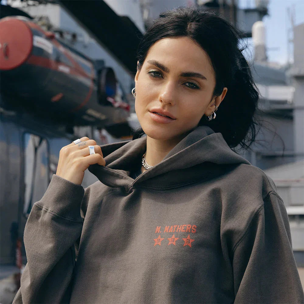 Woman wearing the taupe Eminem Kamikaze x Standard Issue hoodie with orange star print