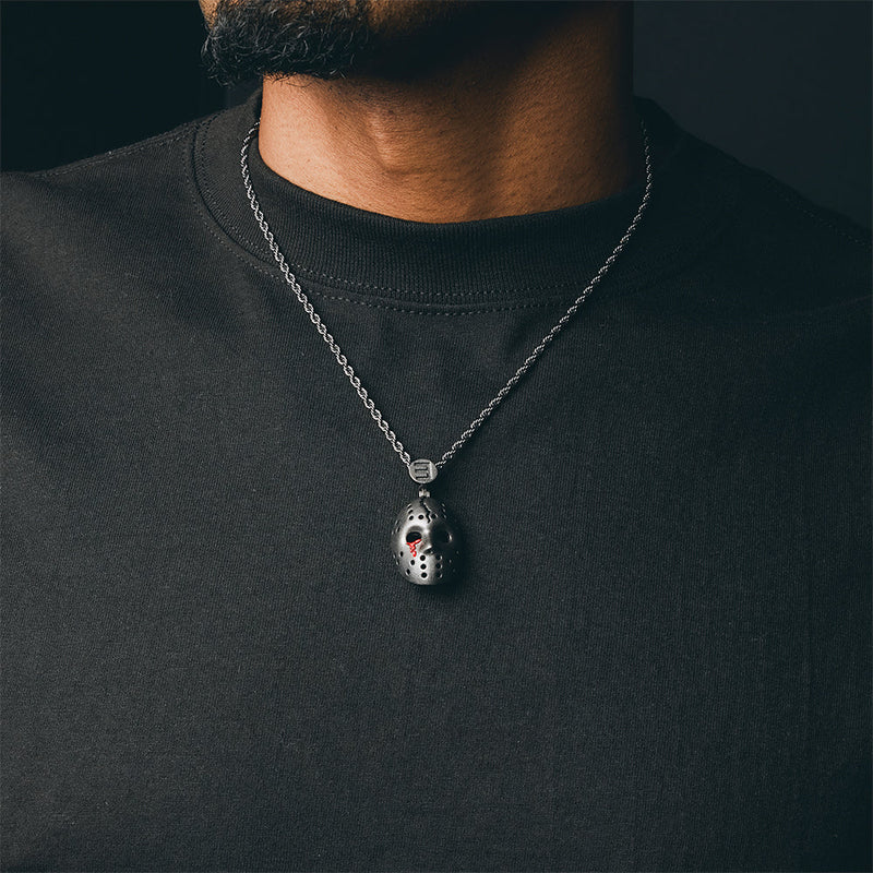 Man wearing the silver Eminem hockey mask pendant and chain over a dark T-shirt