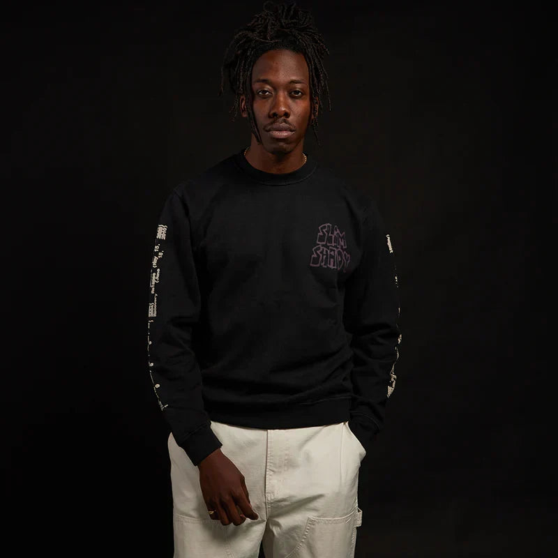 Man wearing the black Eminem Graffiti Slim crewneck with small chest print and sleeve text