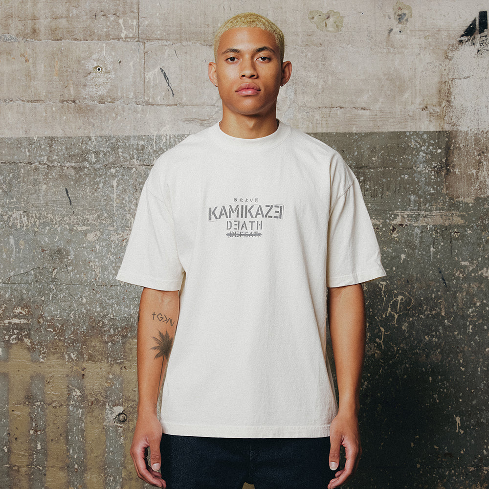 Man wearing the cream Eminem Kamikaze Propaganda T-shirt with tonal chest print