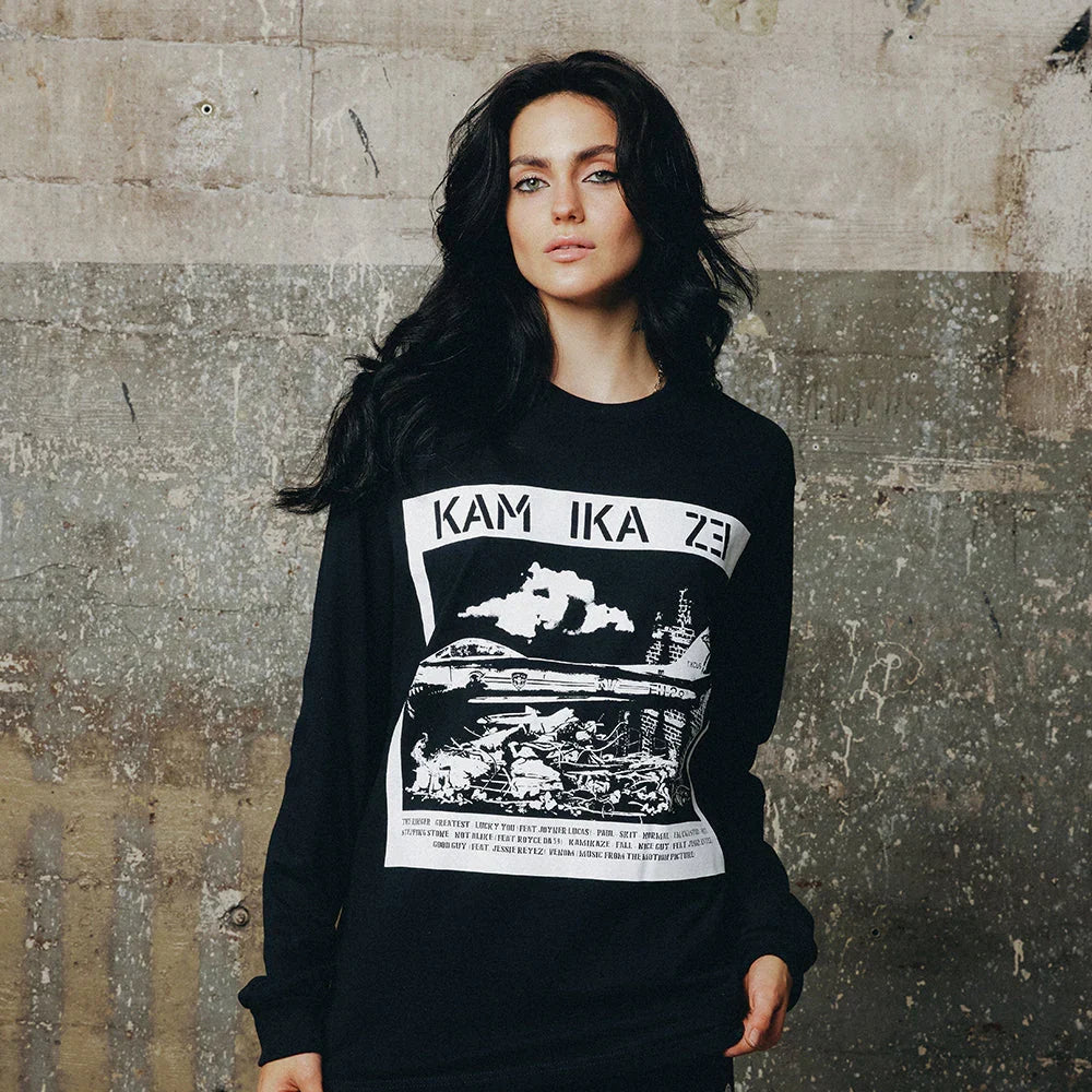 Woman wearing the black Eminem Kamikaze Rubble long sleeve shirt against a concrete wall