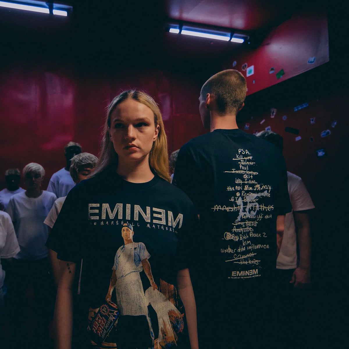 Two models showing front and back of the black Eminem MMLP25 Tracklist T-shirt