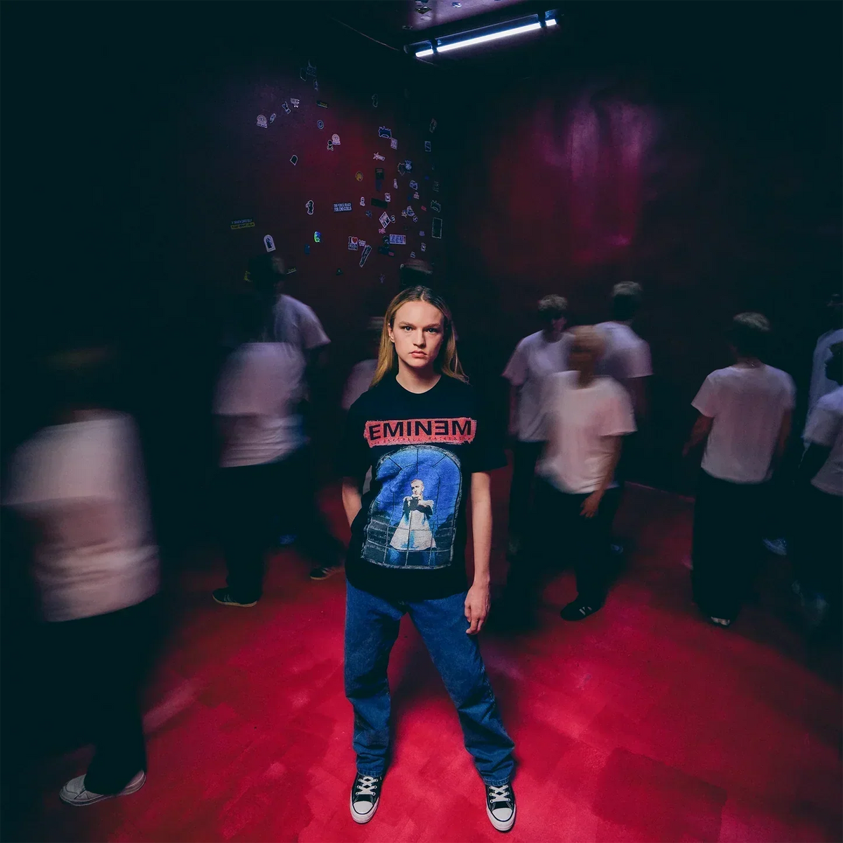 Model in the black Eminem MMLP25 top in a crowd under red and blue lighting