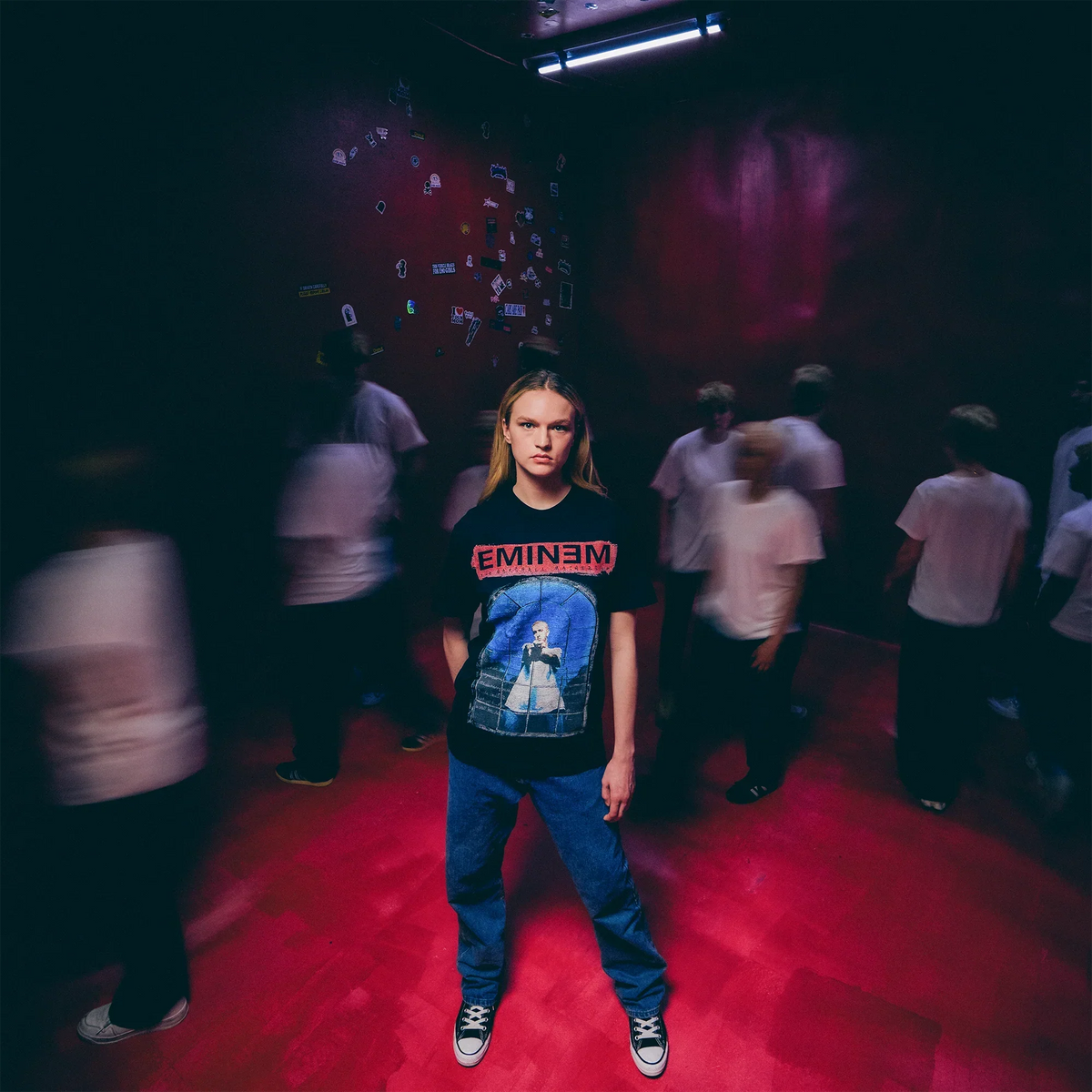 Model in the black Eminem MMLP25 Window T-shirt in a red-lit crowd