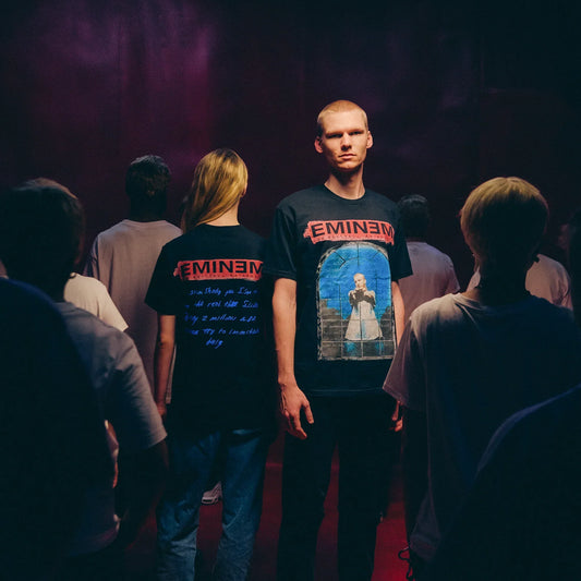 Two models in black Eminem MMLP25 Window T-shirts under red stage lighting