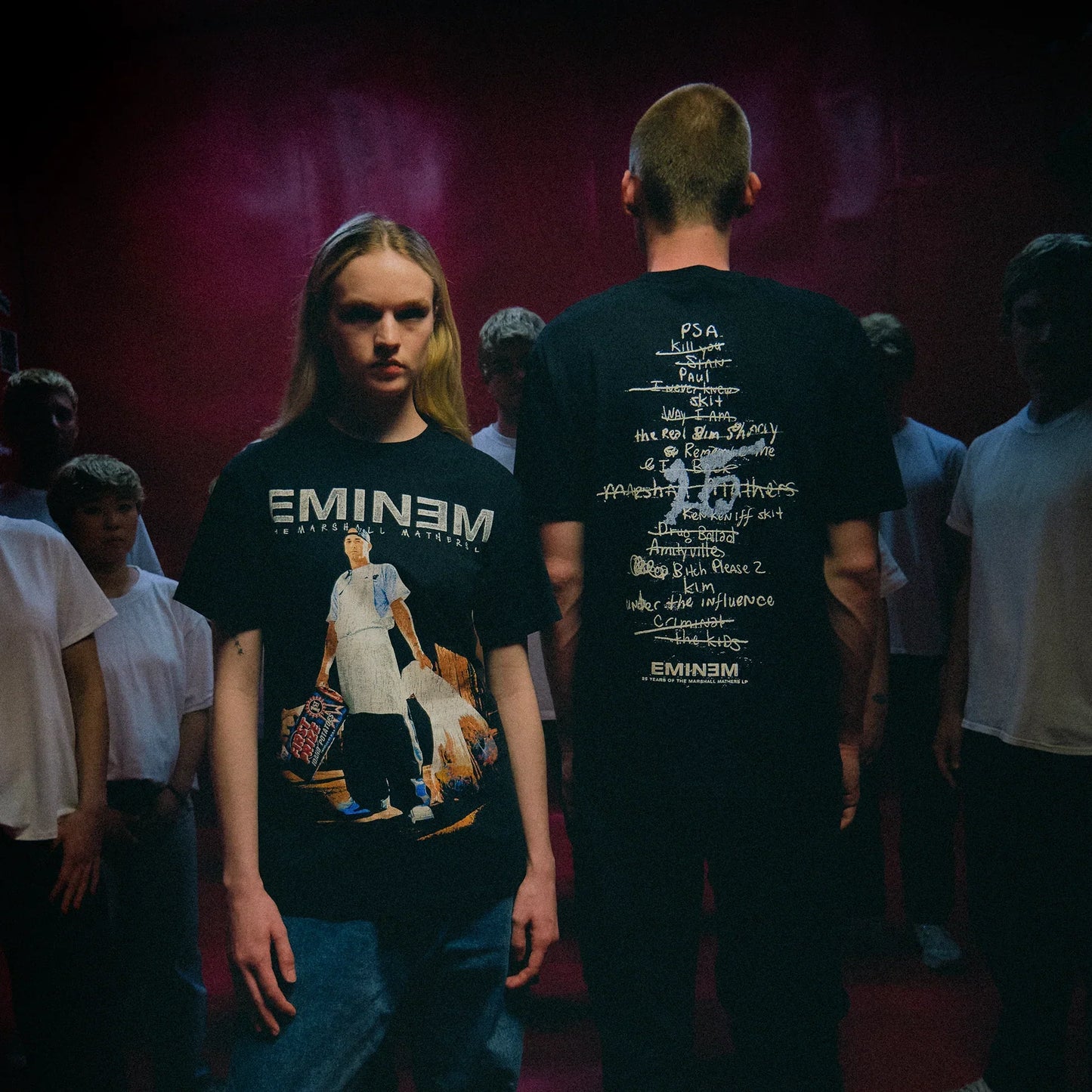 Two models in black Eminem MMLP25 Tracklist T-shirts with front photo and back list prints