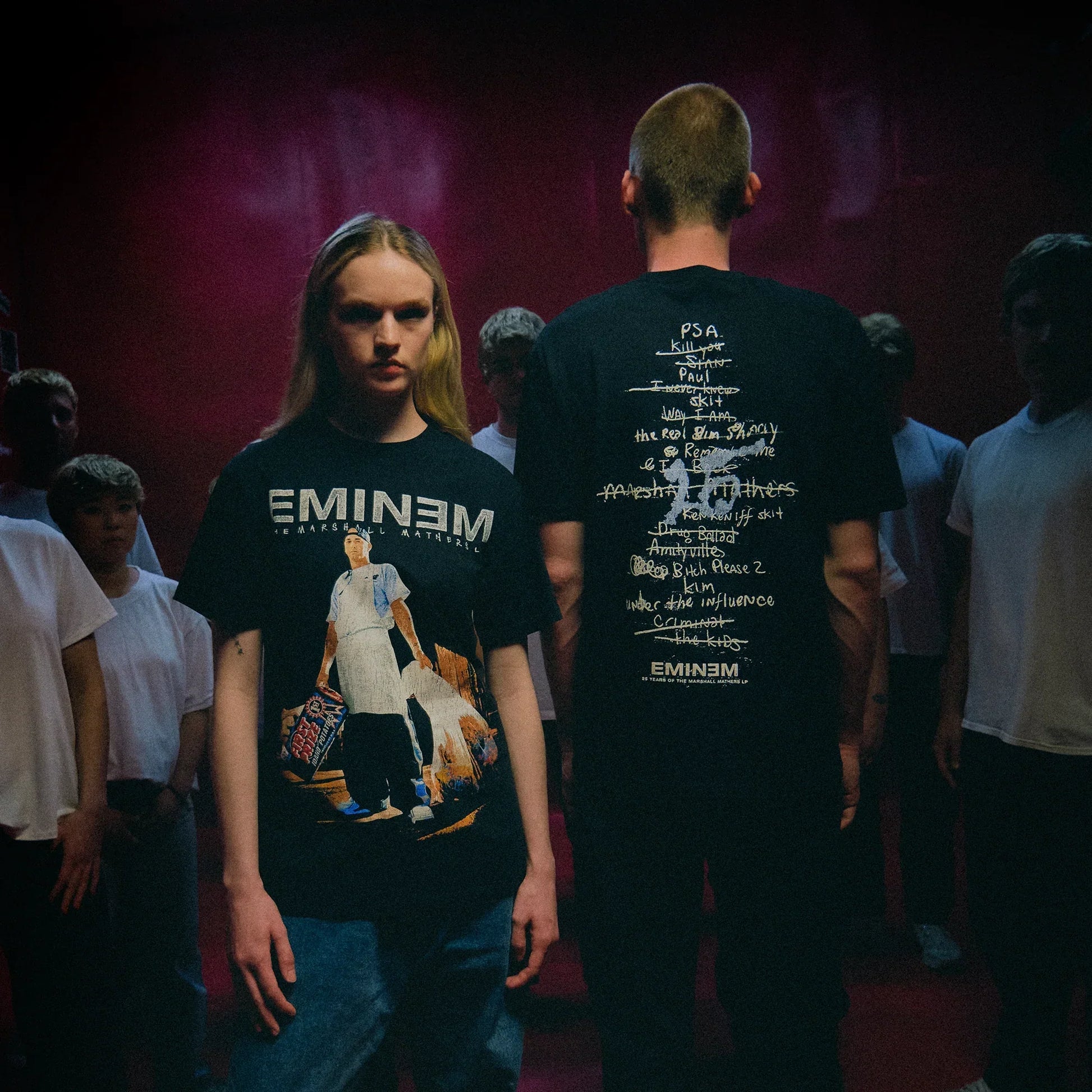 Two models in black Eminem MMLP25 Tracklist T-shirts with front photo and back list prints