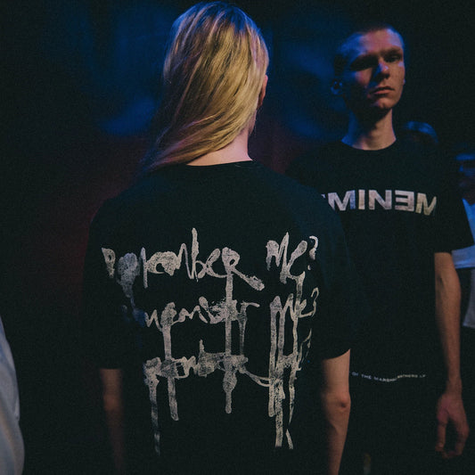 Two models in black Eminem MMLP25 Remember Me T-shirts under blue stage lighting