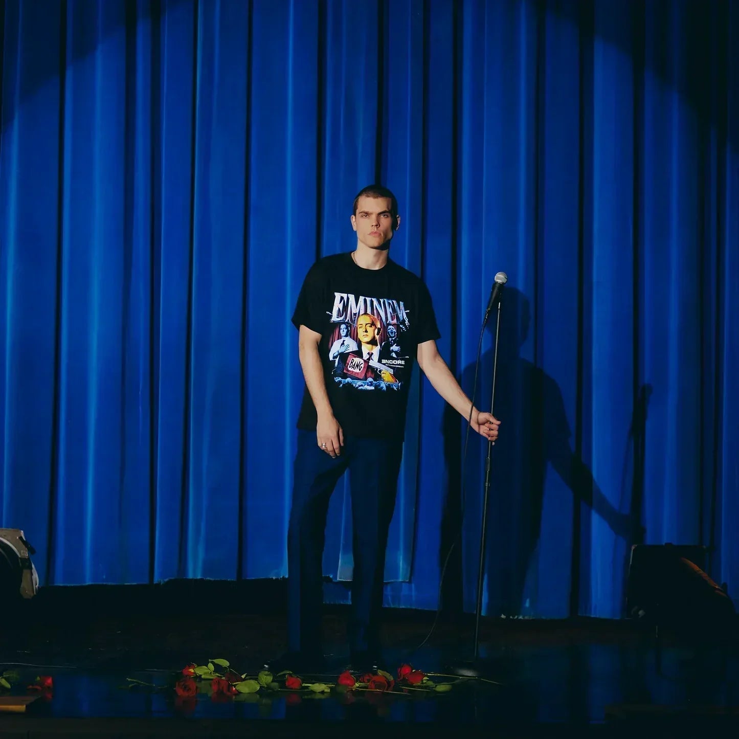 Full-length view of the Eminem Encore 20th Bang Flag T-shirt on a blue-curtained stage