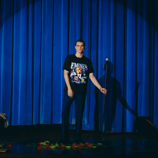 Full-length view of the Eminem Encore 20th Bang Flag T-shirt on a blue-curtained stage