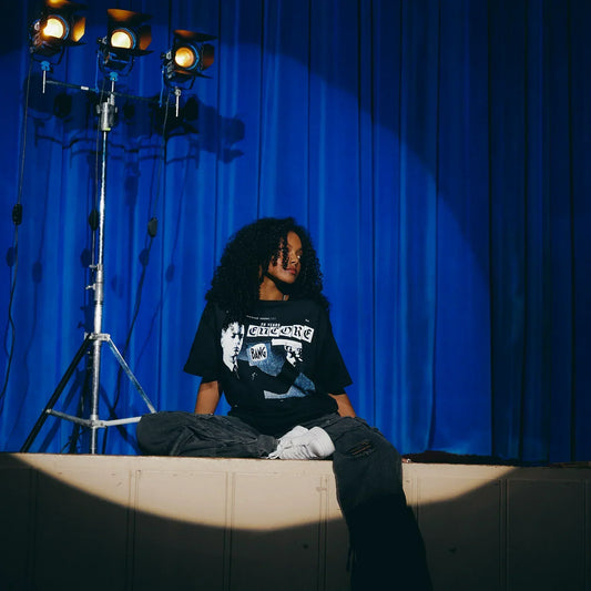 Woman wearing the black Eminem Encore 20th Clippings T-shirt seated on a stage