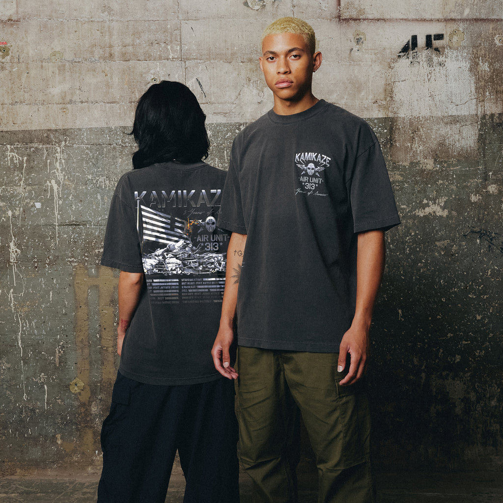 Two models in washed black Eminem Kamikaze Flag T-shirts against a concrete wall