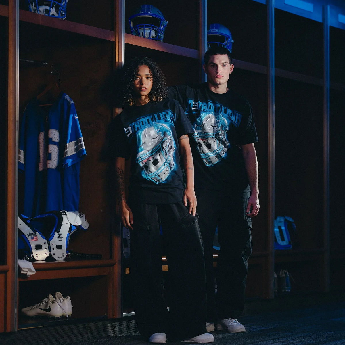 Two models wearing Eminem x Detroit Lions All Grit T-shirts in the team locker room