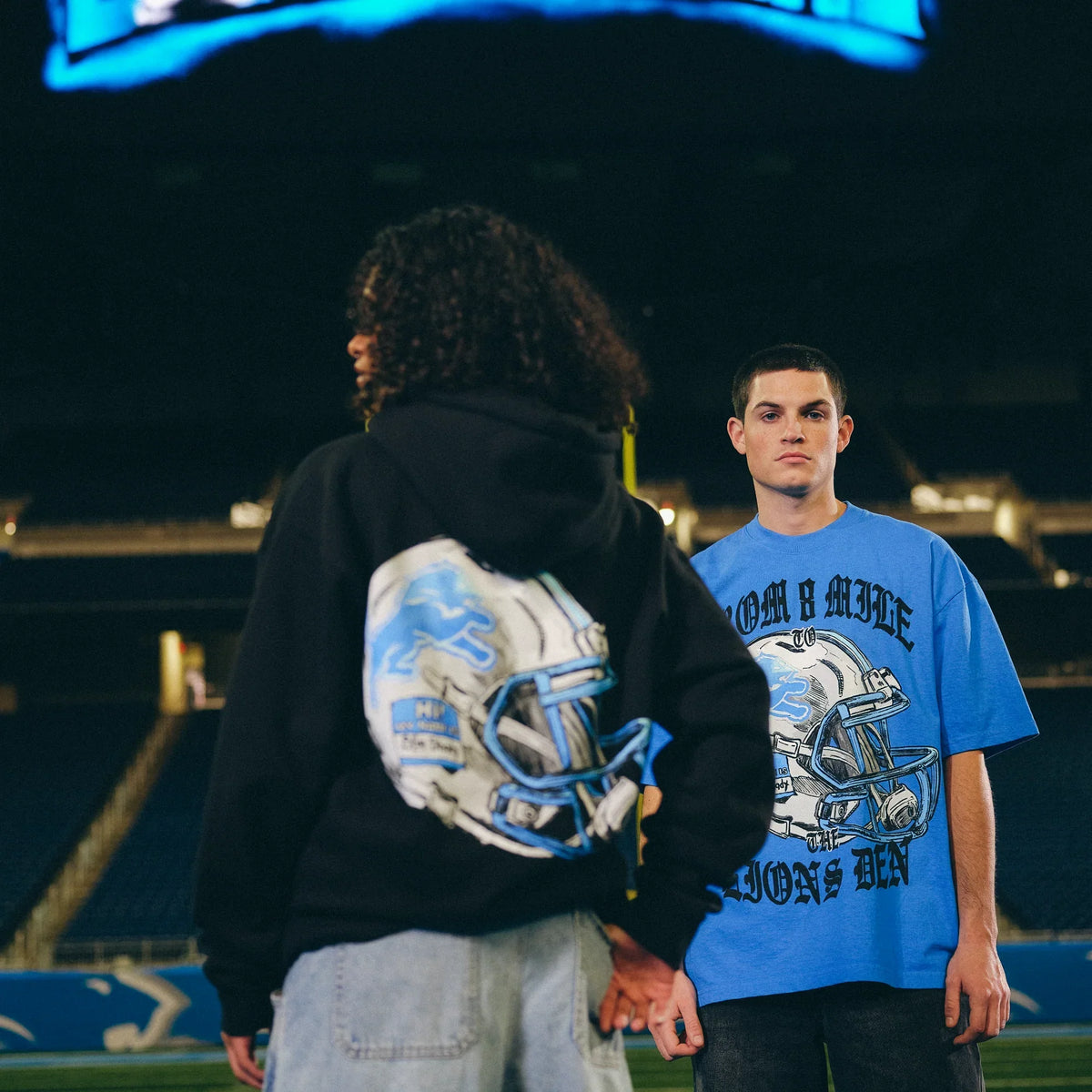 Back view of the Eminem x Detroit Lions helmet graphic on tee and hoodie at Ford Field