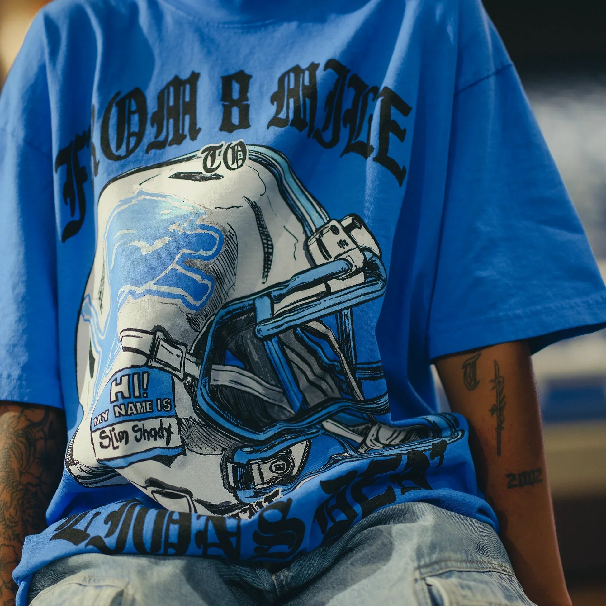 Close-up of the blue Eminem x Detroit Lions T-shirt print, chrome helmet and From 8 Mile lettering