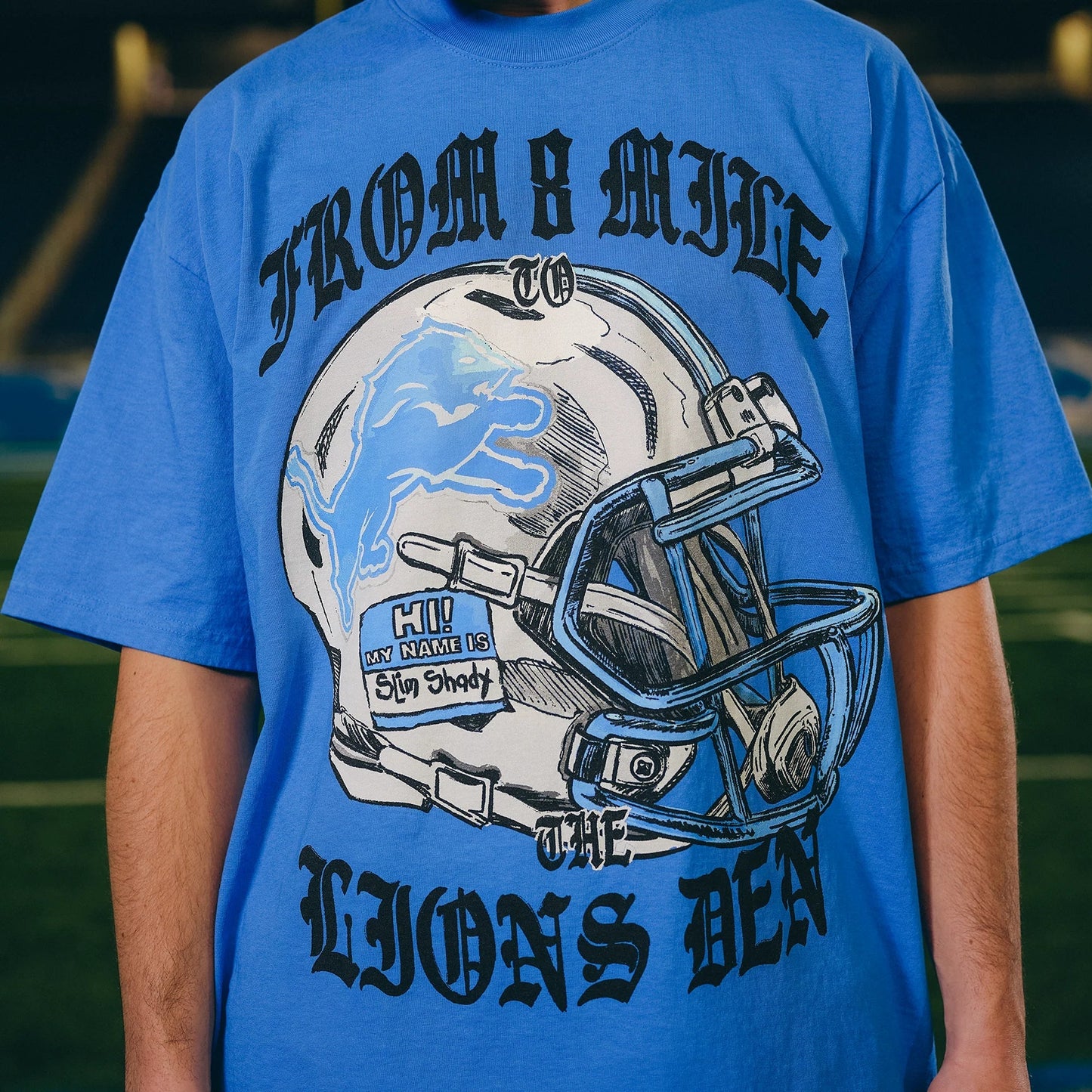 Front print detail of the Eminem x Detroit Lions Helmet T-shirt reading From 8 Mile To The Lions Den
