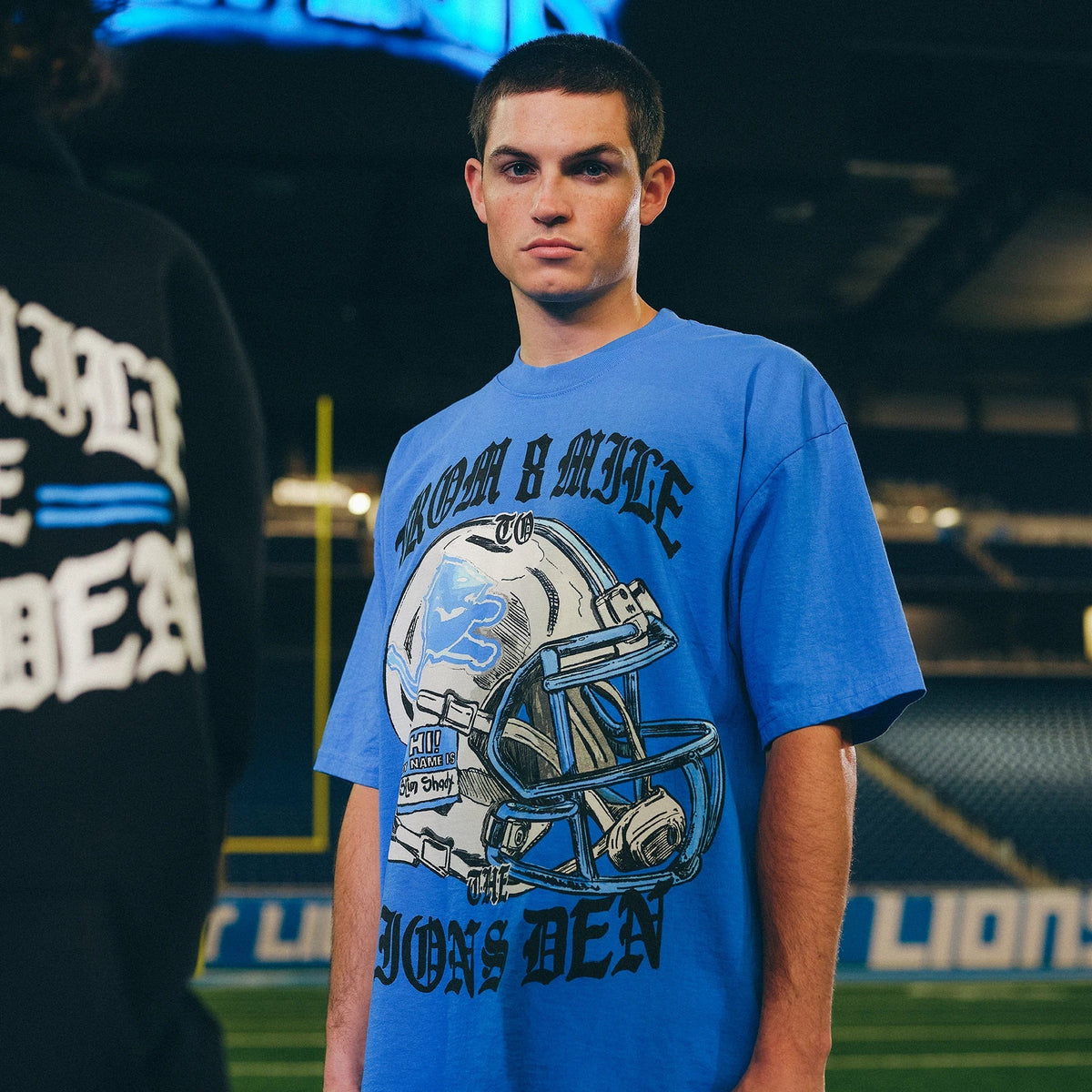 Man wearing the blue Eminem x Detroit Lions Helmet T-shirt on the field