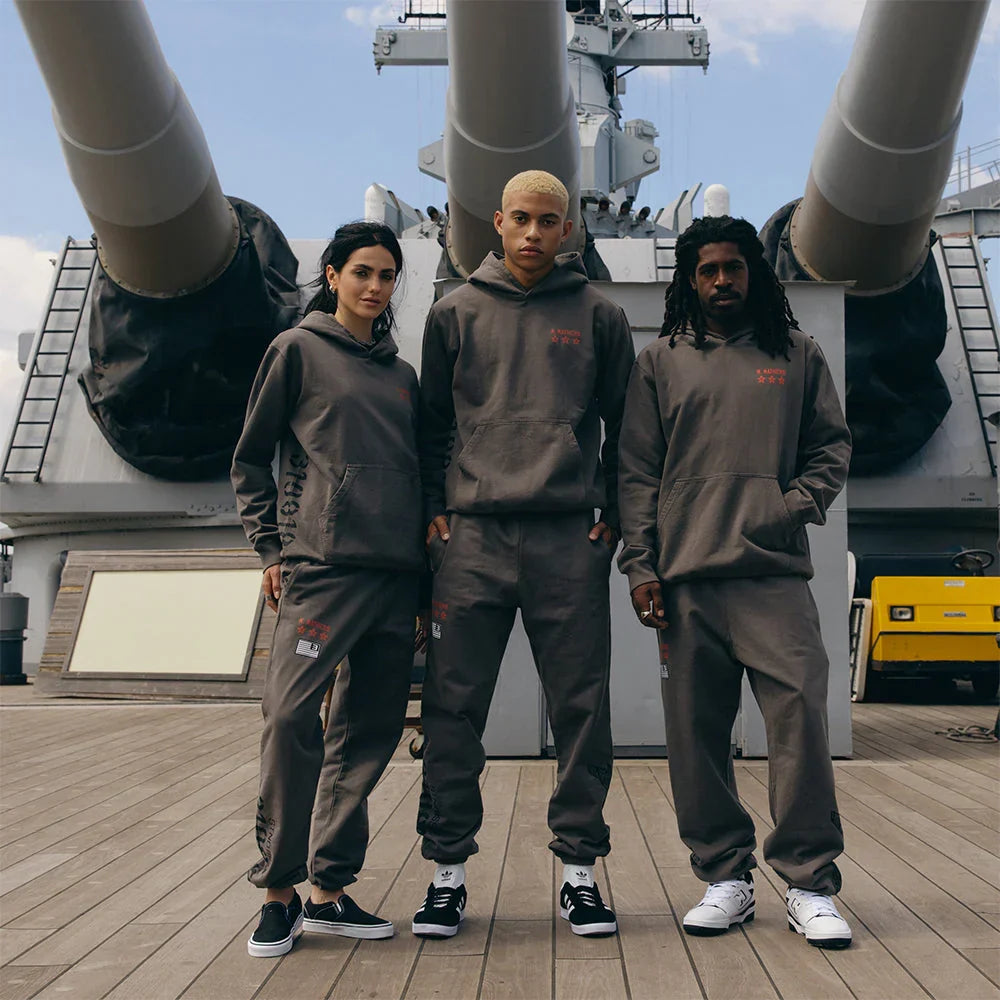 Three models in taupe Eminem Kamikaze x Standard Issue hoodies and joggers on deck