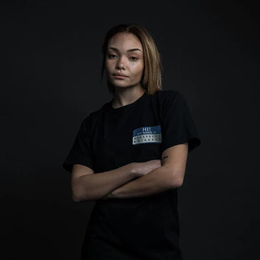 Woman wearing the black Eminem Hi! My Name Is T-shirt with blue name tag chest print