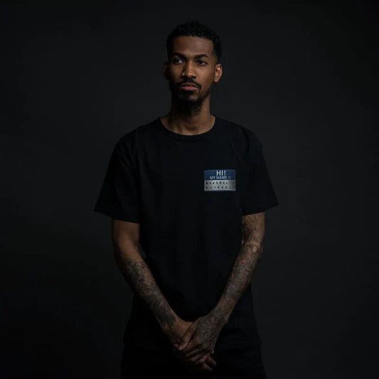 Man wearing the black Eminem Hi! My Name Is blue name tag reissue T-shirt