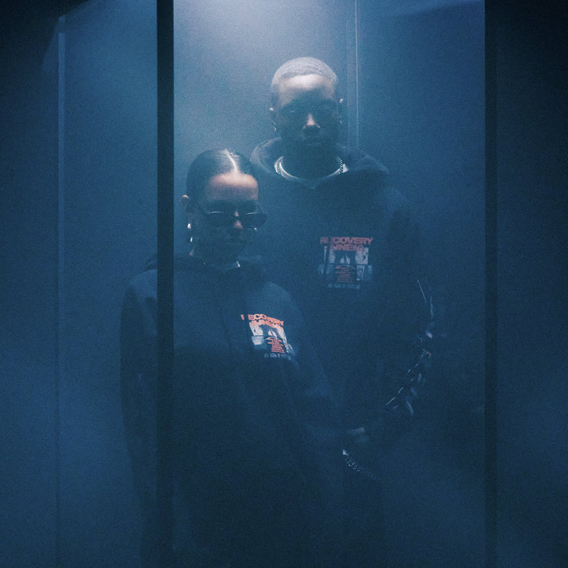Models in Eminem Recovery Anniversary hoodies reflected in blue-lit glass