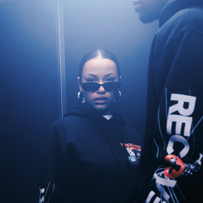 Woman wearing the black Eminem Recovery 15th Anniversary hoodie with Recovery sleeve print