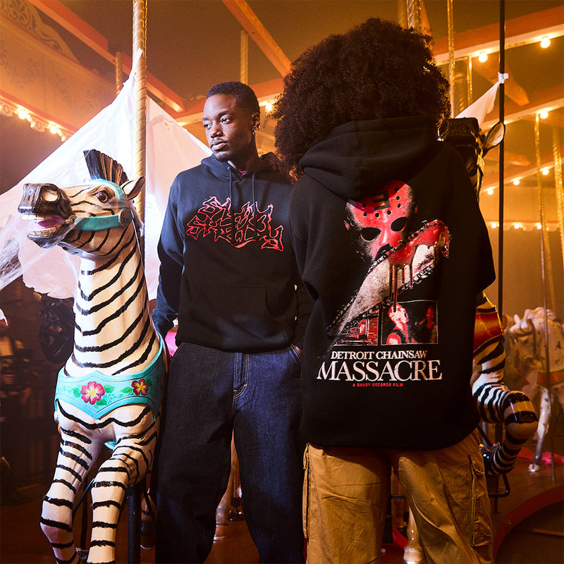 Two models in Eminem Massacre hoodies at a fairground, red Detroit Chainsaw Massacre print