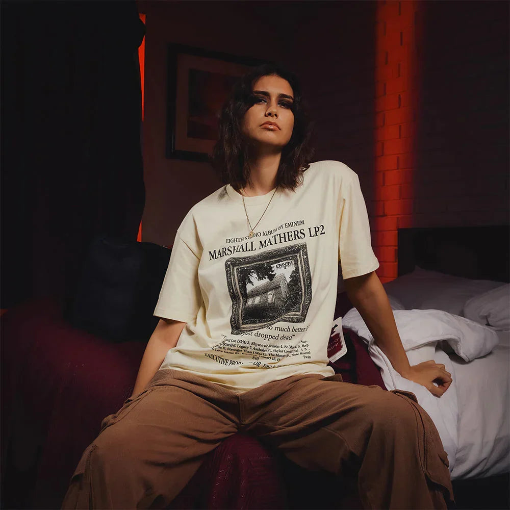 Woman wearing the cream Eminem MMLP2 album T-shirt with house photo artwork