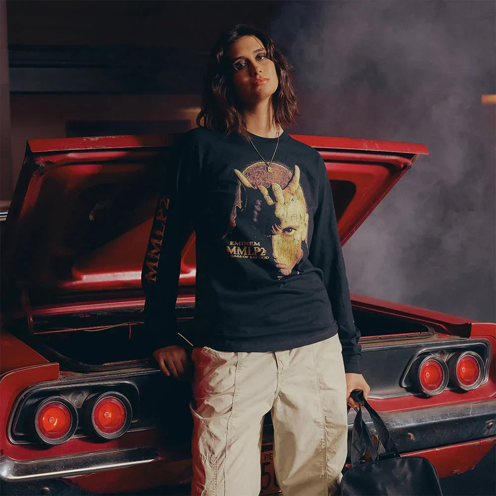 Woman wearing the black Eminem MMLP2 Horns long sleeve beside a muscle car