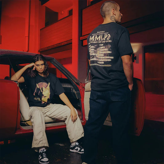 Two models in black Eminem MMLP2 Horns T-shirts in a red-lit motel corridor