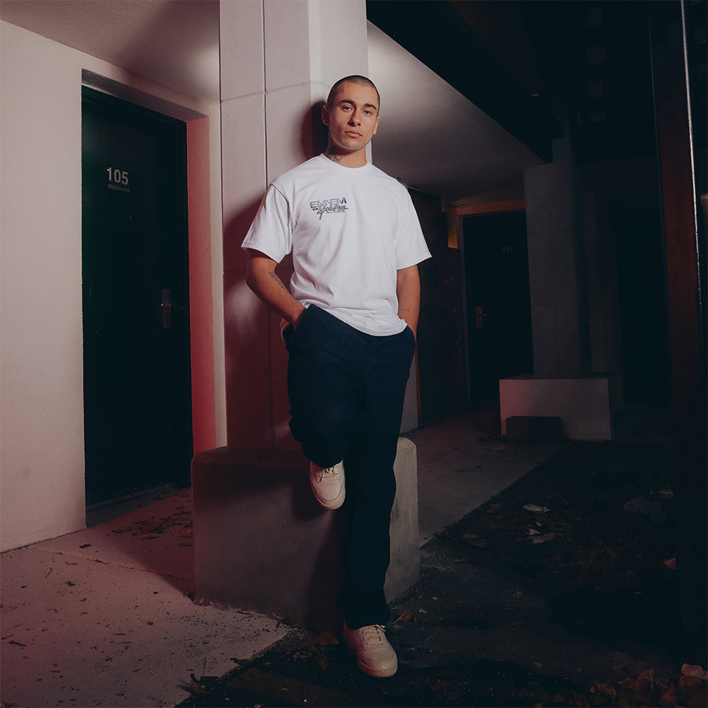 Man wearing the white Eminem MMLP2 Monster Tour T-shirt, front logo print