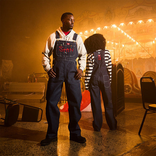 Two models in Eminem Stan denim overalls at a fairground at night