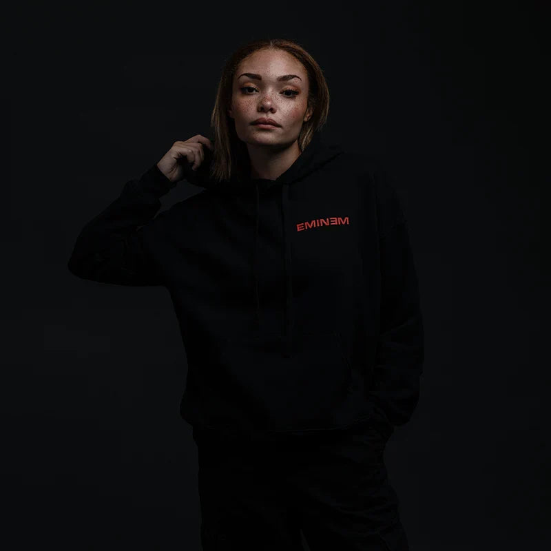 Woman wearing the black Eminem Powerline hoodie, hood up, red chest print