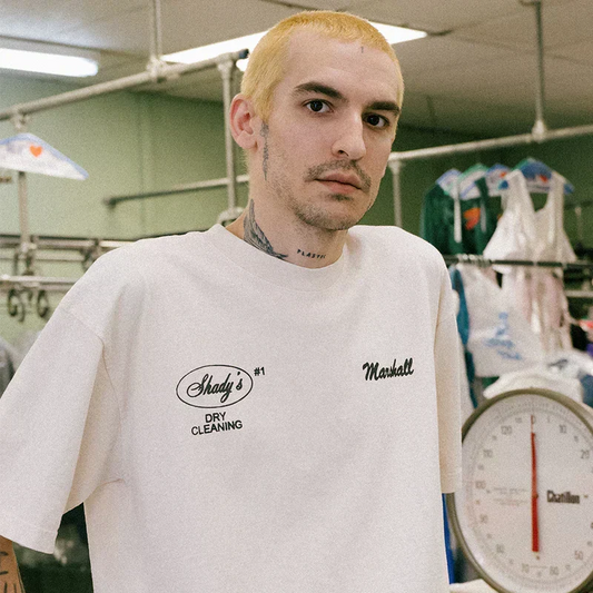 Man wearing the cream Eminem Shady Cleaners T-shirt in a dry cleaning shop