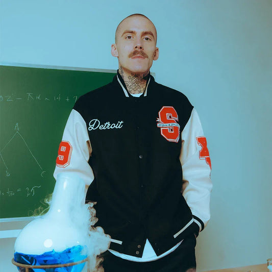 Man wearing the Eminem SSLP25 varsity jacket with cream sleeves and chenille patches