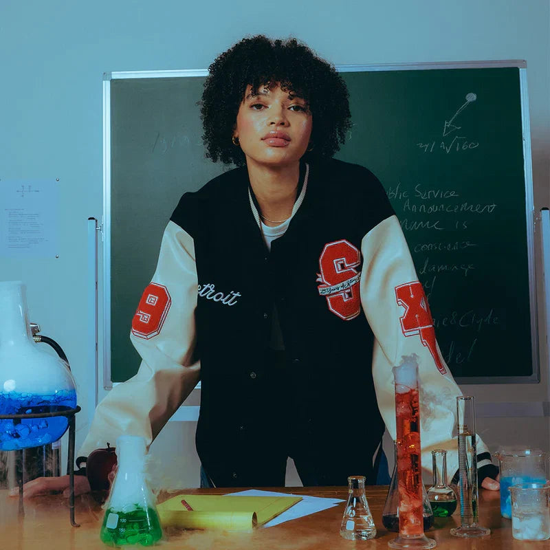 Woman wearing the Eminem SSLP25 varsity jacket with Detroit script and S patch