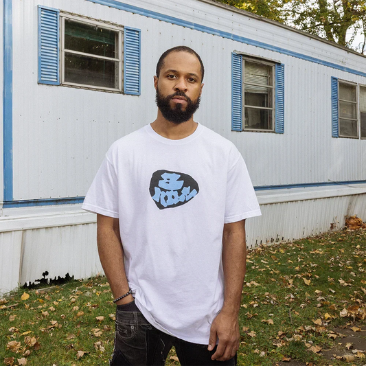 Man in white Eminem 8 Mile Graffiti T-shirt with small blue graffiti chest print, trailer park backdrop