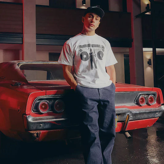 Man in the white Eminem Berzerk T-shirt leaning on a red muscle car, boombox graphic print