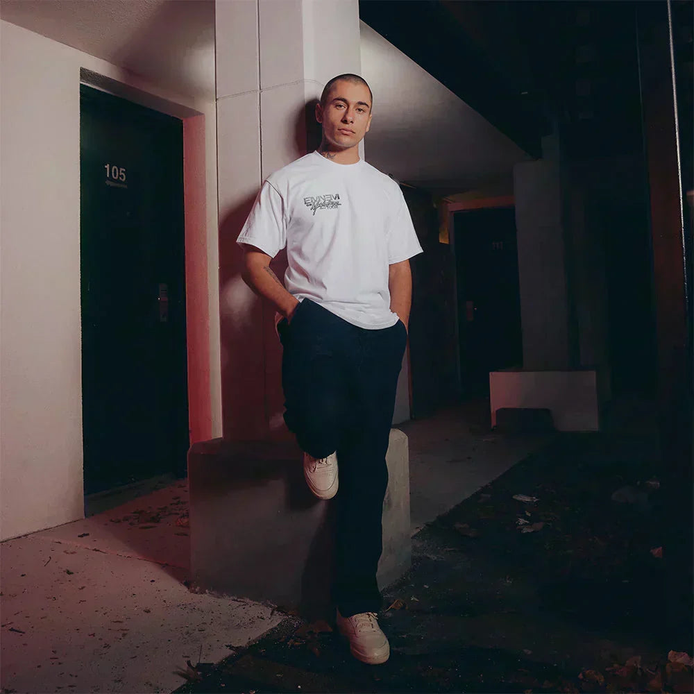 Man wearing the white Eminem Monster Tour T-shirt in a red-lit corridor