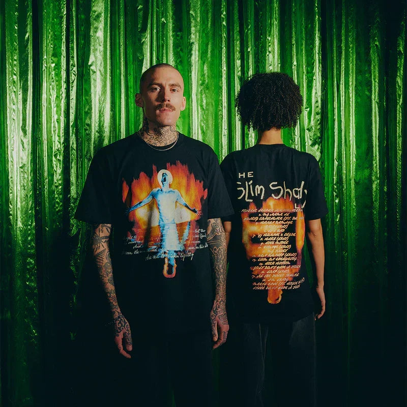 Two models in black Eminem SSLP25 Fire T-shirts against a green backdrop