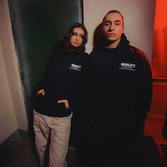 Two models wearing black Eminem MMLP2 Condemned hoodies in a red-lit hallway