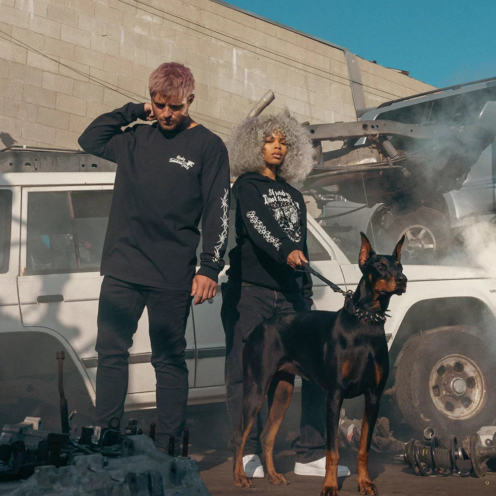 Two models in Eminem Shady Demolition merch with a doberman in a wrecking yard