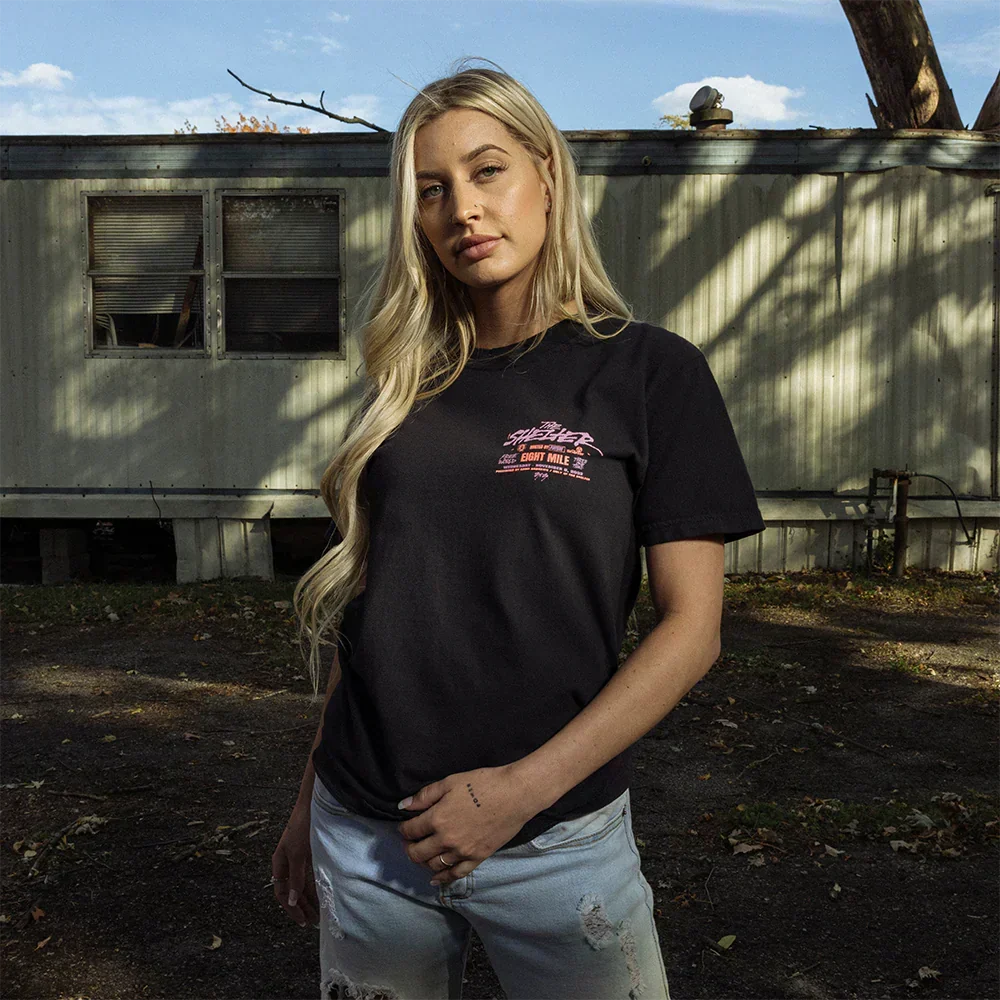 Woman wearing the black Eminem Shelter event T-shirt with pink chest print